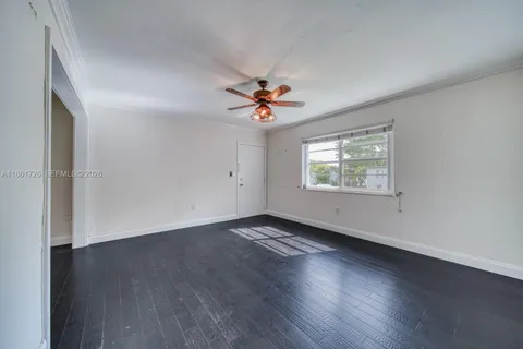 an empty room with wooden floor and ceiling fan