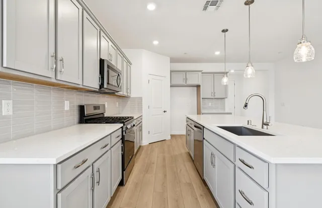 a kitchen with stainless steel appliances granite countertop a sink a stove and a refrigerator