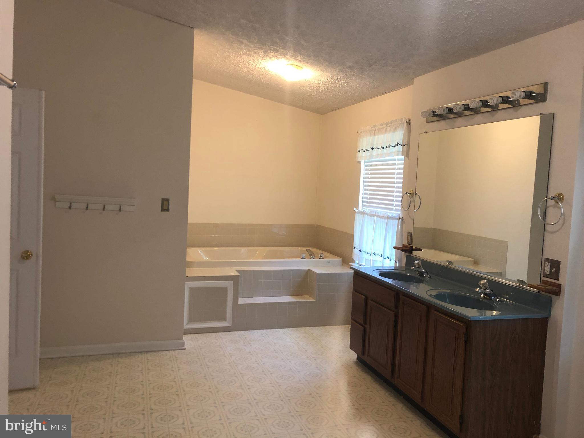 11234 Commanche Road Lusby, MD 20657 - Photo 9 of 21 a bathroom with a granite countertop sink and a bathtub