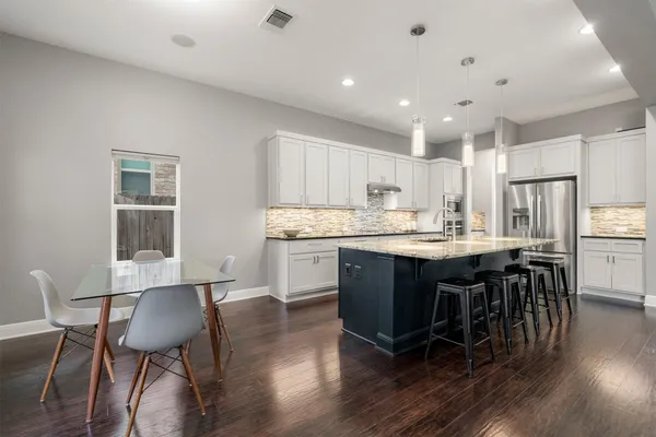 a kitchen with a dining table chairs and wooden floor