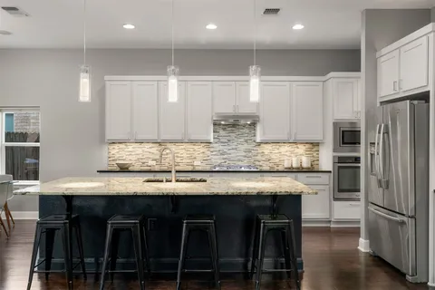 a kitchen with stainless steel appliances granite countertop a table chairs sink refrigerator and microwave