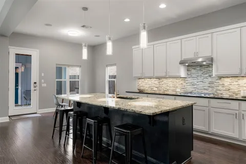 a kitchen with stainless steel appliances granite countertop a table chairs sink and cabinets
