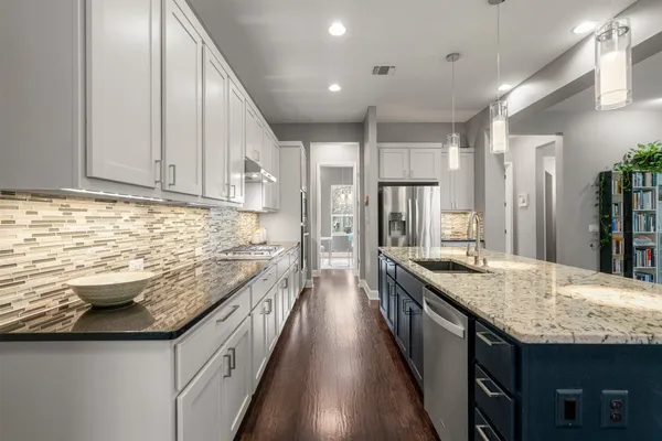 a kitchen with granite countertop kitchen island stainless steel appliances a sink stove and cabinets