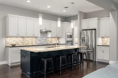 a kitchen with stainless steel appliances granite countertop a table chairs sink refrigerator and cabinets