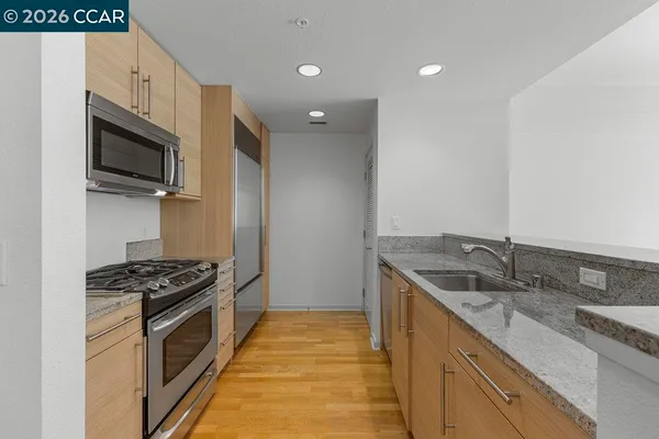a kitchen with granite countertop stainless steel appliances a sink stove top oven and wooden floor