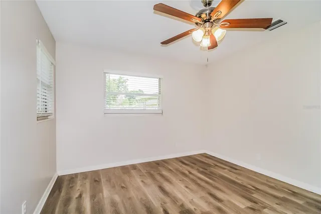 an empty room with a window and a fan