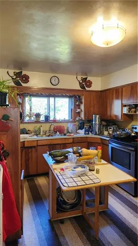 a kitchen with a stove a sink dishwasher and a dining table with wooden floor