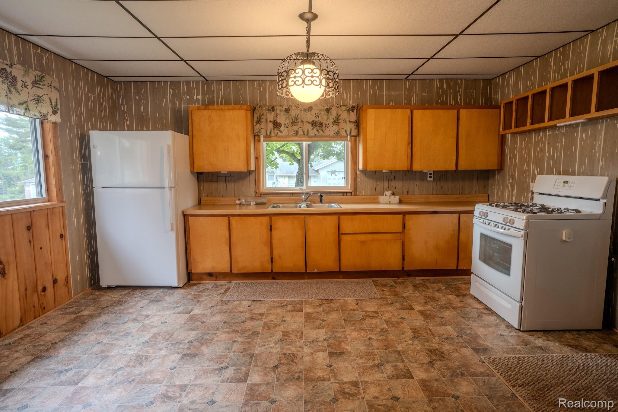 4350 Shrew Road Lincoln, MI 48742 - Photo 8 of 32 Kitchen featuring ample natural light, a white freestanding gas range, a white top-freezer refrigerator, wood-finish cabinetry, and patterned floor tiling