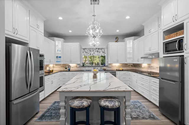 a kitchen with a refrigerator a sink dishwasher a stove and white cabinets with wooden floor