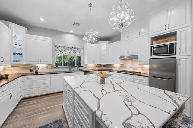a kitchen with stainless steel appliances kitchen island granite countertop a kitchen island hardwood floor and a sink