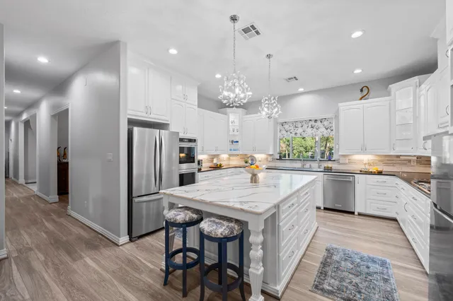 a kitchen with stainless steel appliances white cabinets a sink and a large window