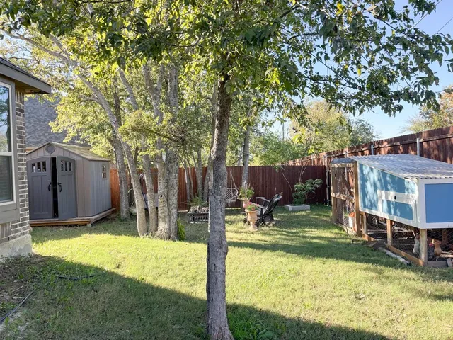 a view of a backyard with table and chairs and a large tree