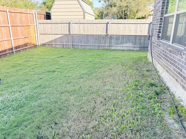 a view of backyard with wooden fence