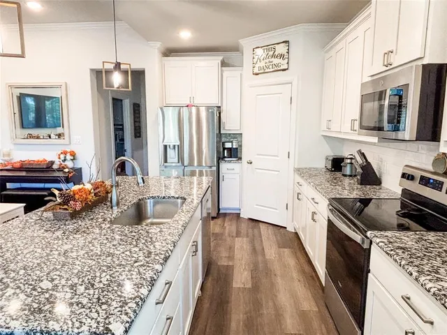 a kitchen with stainless steel appliances granite countertop a refrigerator a stove top oven a sink dishwasher and wooden cabinets