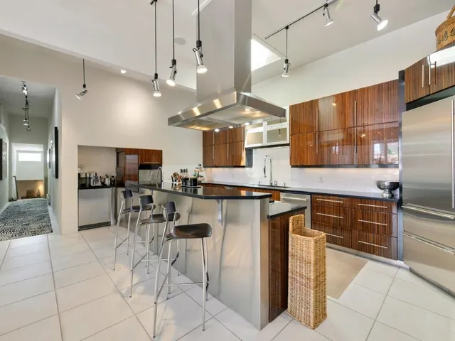 a kitchen with stainless steel appliances kitchen island granite countertop a table chairs sink and cabinets