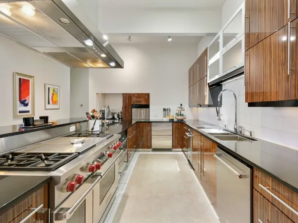 a large kitchen with stainless steel appliances granite countertop a large stove a sink dishwasher and cabinets with wooden floor