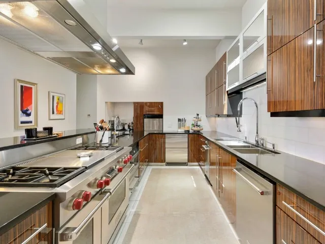 a large kitchen with stainless steel appliances granite countertop a large stove a sink dishwasher and cabinets with wooden floor