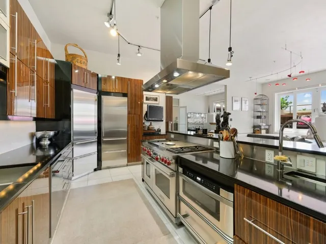 a kitchen with stainless steel appliances granite countertop a sink a stove and a refrigerator