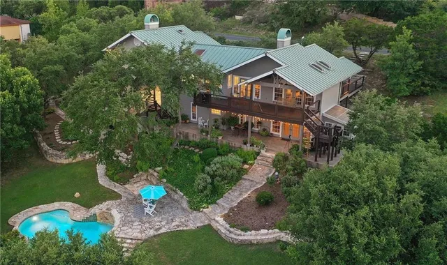 an aerial view of a house with garden space and trees all around