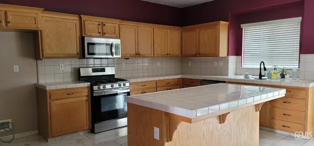 a kitchen with stainless steel appliances granite countertop a sink stove and microwave