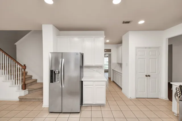 a kitchen with a refrigerator and white cabinets
