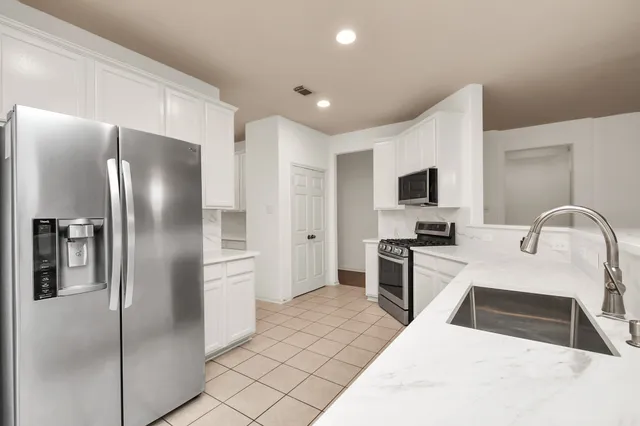 a kitchen with stainless steel appliances granite countertop a refrigerator a stove a sink and a microwave