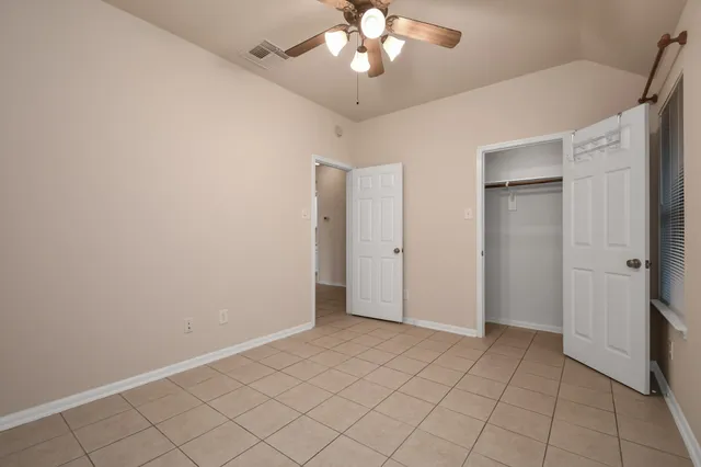 an empty room with closet and a chandelier fan