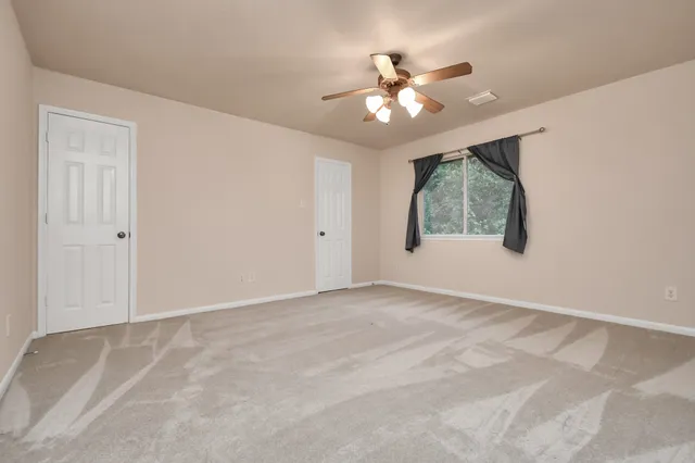 a view of an empty room with chandelier fan