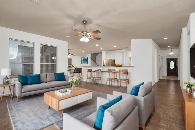 a living room with furniture kitchen view and a large window