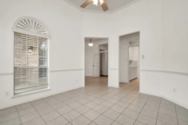 an empty room with chandelier fan and windows