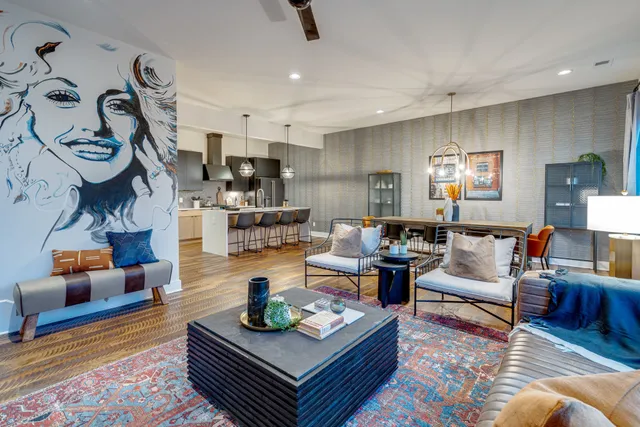 a living room with furniture kitchen view and a wooden floor