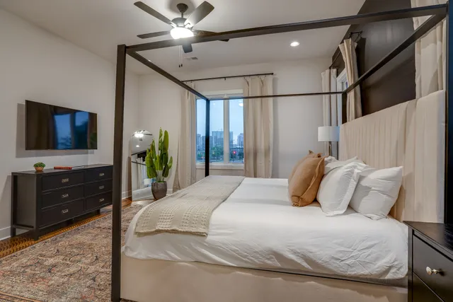a bedroom with a bed and a flat tv screen on dresser