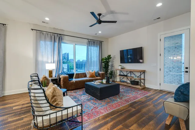 a living room with furniture a flat screen tv and a large window