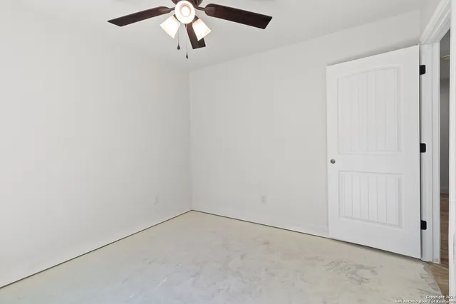 an empty room with a ceiling fan and carpet