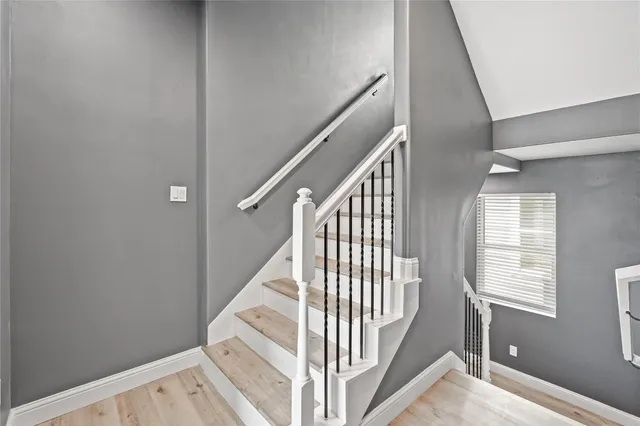 a view of staircase with railing and white walls