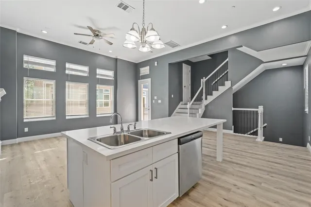 a large white kitchen with lots of counter space a sink appliances and cabinets