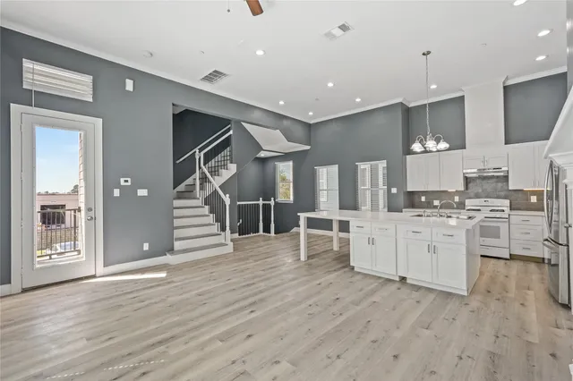 a large white kitchen with stainless steel appliances granite countertop a refrigerator and a stove top oven