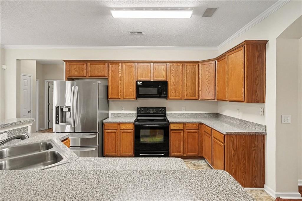 1558 Kilgore Road Griffin, GA 30223 - Photo 11 of 32 a kitchen with stainless steel appliances granite countertop a stove a sink and a refrigerator with cabinets