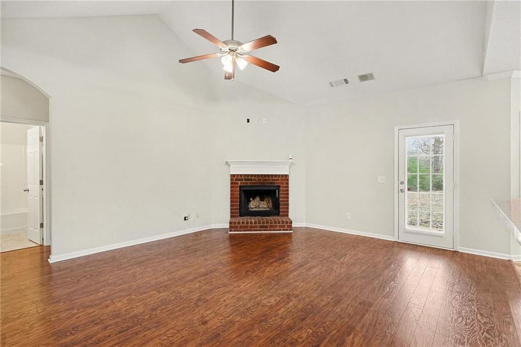 1558 Kilgore Road Griffin, GA 30223 - Photo 6 of 32 an empty room with wooden floor a fireplace a ceiling fan and wooden floor