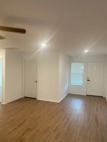 a view of an empty room with wooden floor and closet