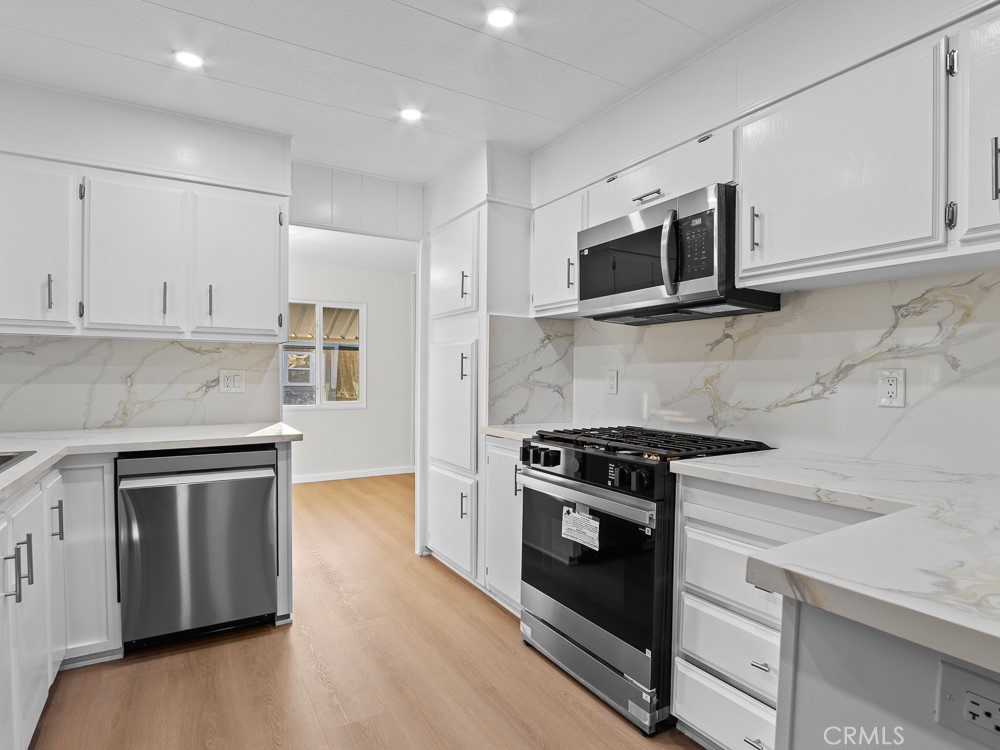 a kitchen with stainless steel appliances granite countertop a stove a microwave and white cabinets