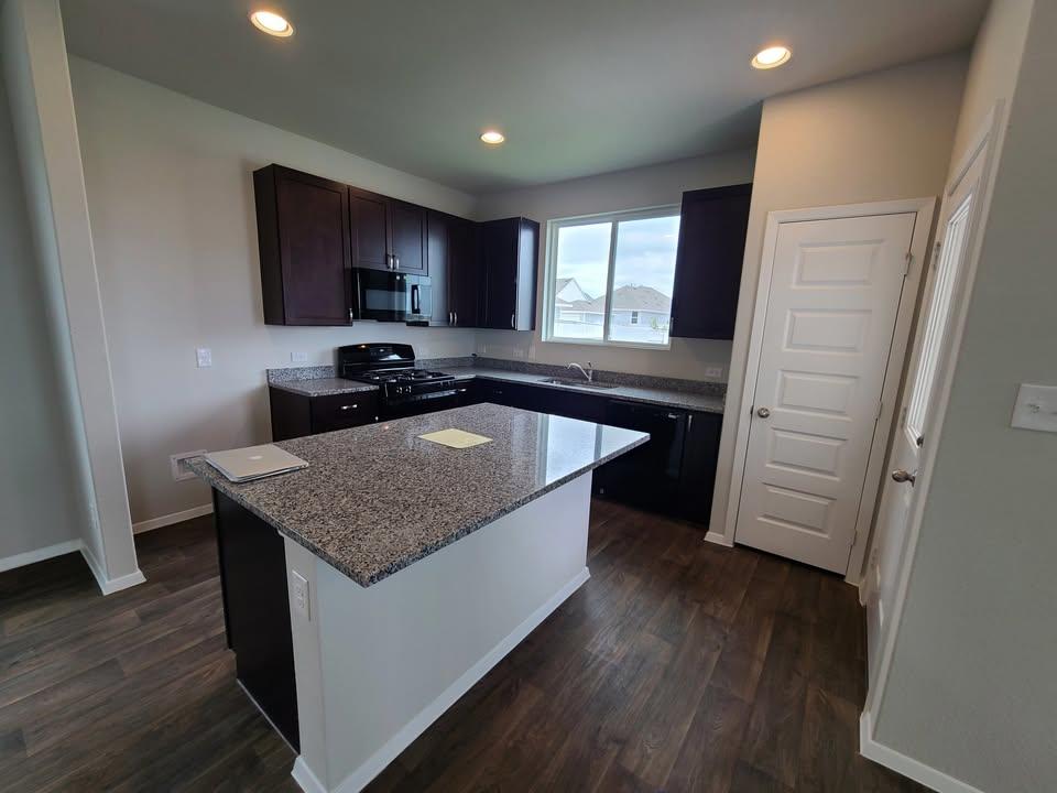 156 Huckleberry Lane Elgin, TX 78621 - Photo 3 of 16 An open-concept kitchen features a large granite-topped island and modern appliances.