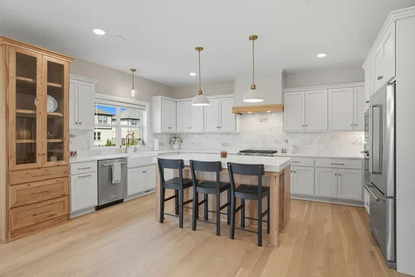 a kitchen with stainless steel appliances granite countertop a dining table chairs sink refrigerator and cabinets