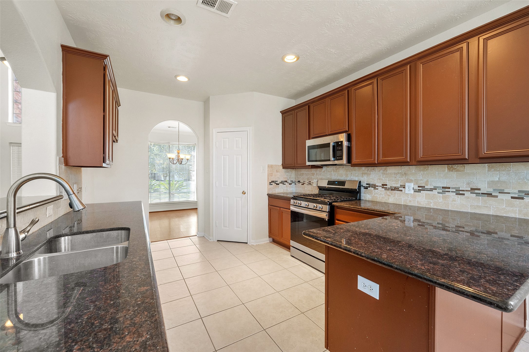 14213 Stone Bluff Lane Rosharon, TX 77583 - Photo 15 of 44 a kitchen with granite countertop a stove a sink and a microwave