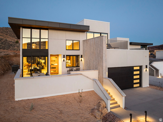 213 Lionsback Loop, Unit 38 Moab, UT 84532 - Photo 20 of 26 Contemporary exterior featuring a flat roofline, stucco finish, large format windows, a modern wood-panel entry door, and an integrated garage with frosted glass inserts