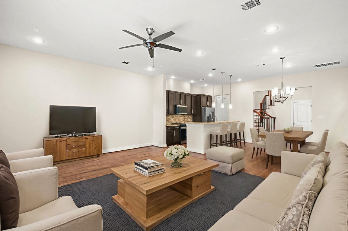 4409 Schuler Street, Unit A Houston, TX 77007 - Photo 10 of 33 The main living area features a central ceiling fan and recessed lighting, with a view highlighting the transition from the kitchen island to the staircase and entry door. **This room has been virtually staged.