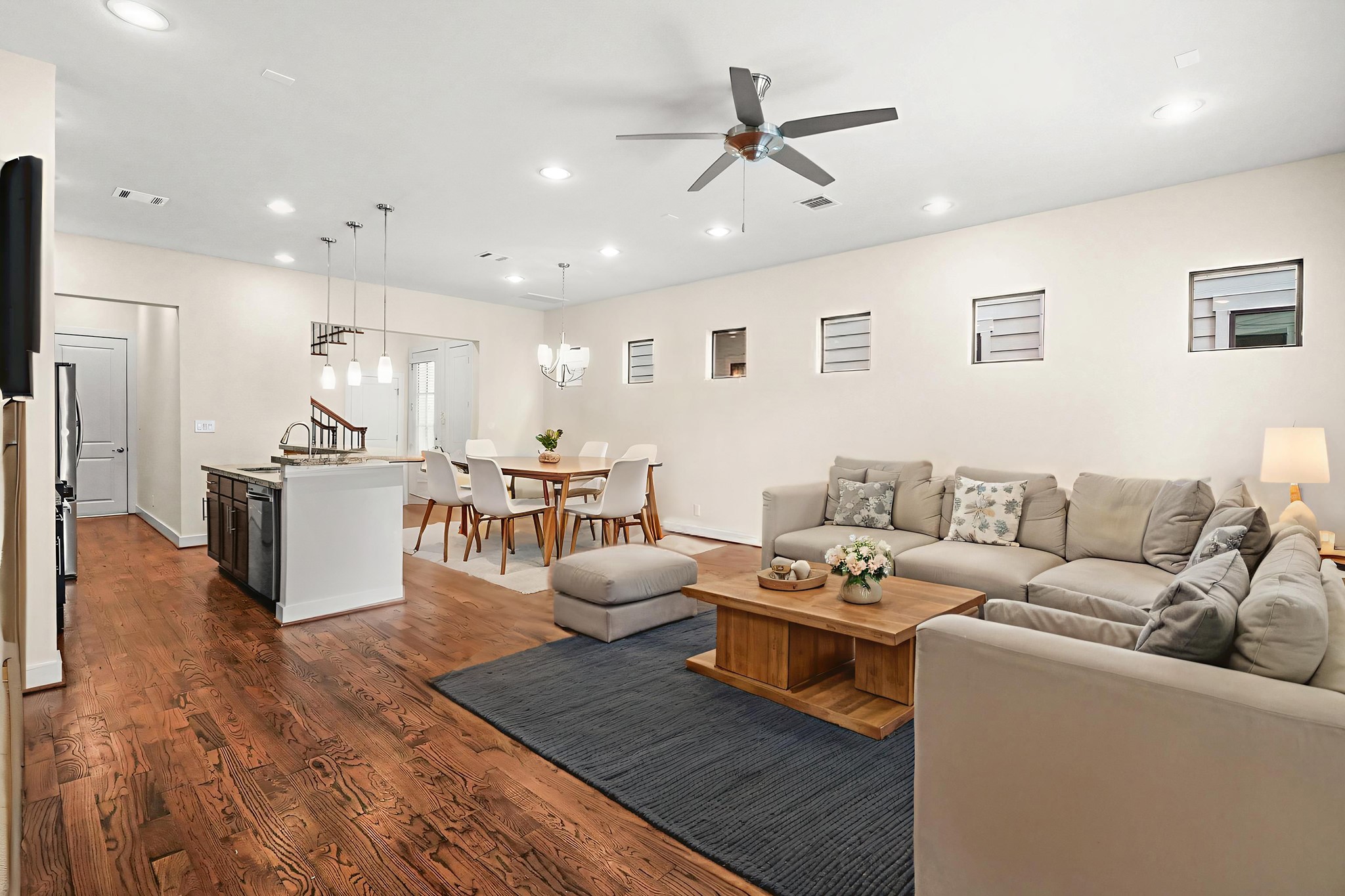 4409 Schuler Street, Unit A Houston, TX 77007 - Photo 11 of 33 This wide-angle view highlights the main level’s continuous wood flooring and high ceilings, with multiple windows and a glass-inset door bringing in abundant natural light. **This room has been virtually staged.