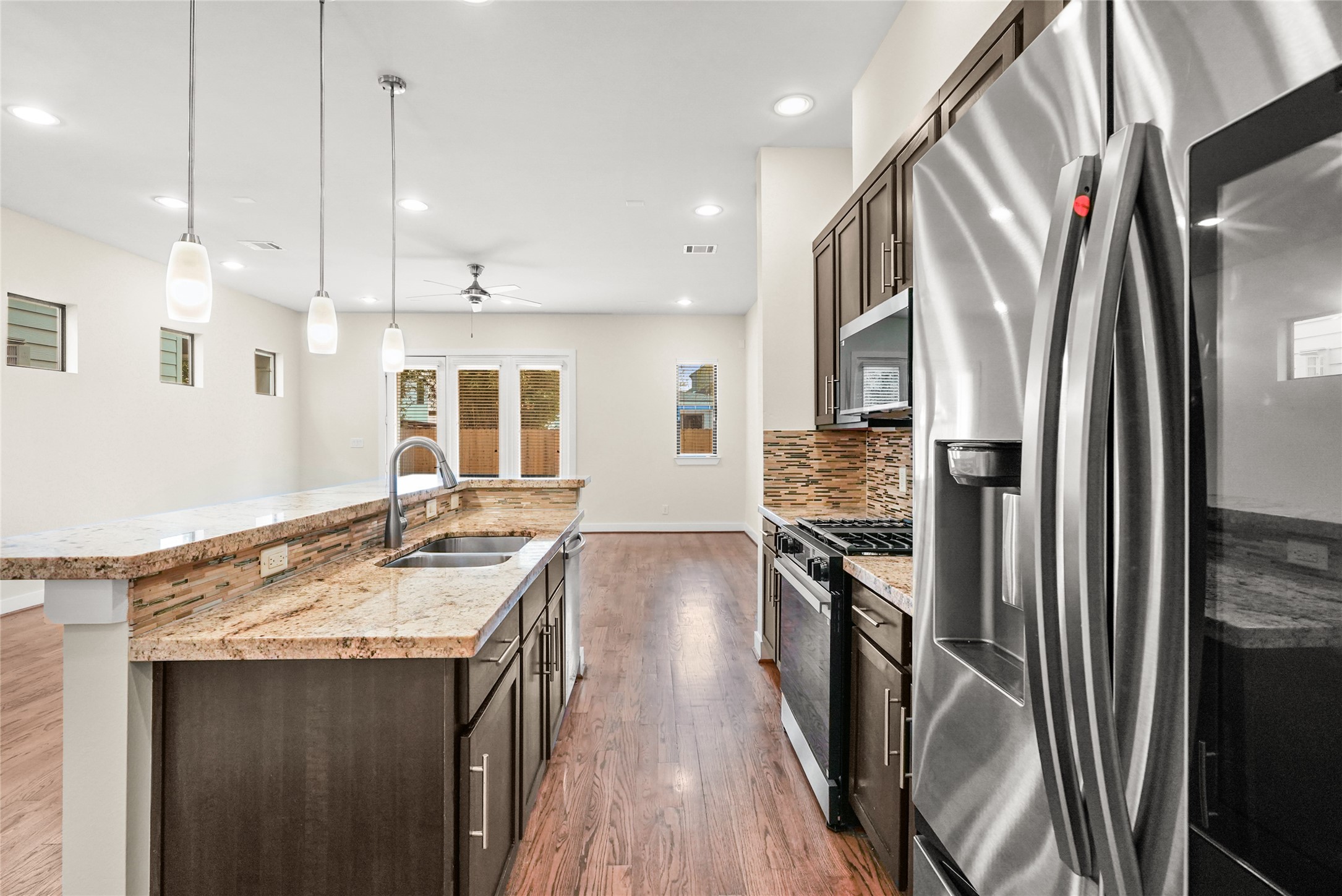 4409 Schuler Street, Unit A Houston, TX 77007 - Photo 13 of 33 The kitchen workspace includes a double-basin stainless steel sink and a gooseneck faucet. A French door refrigerator and a gas range are integrated into the dark wood cabinet run.