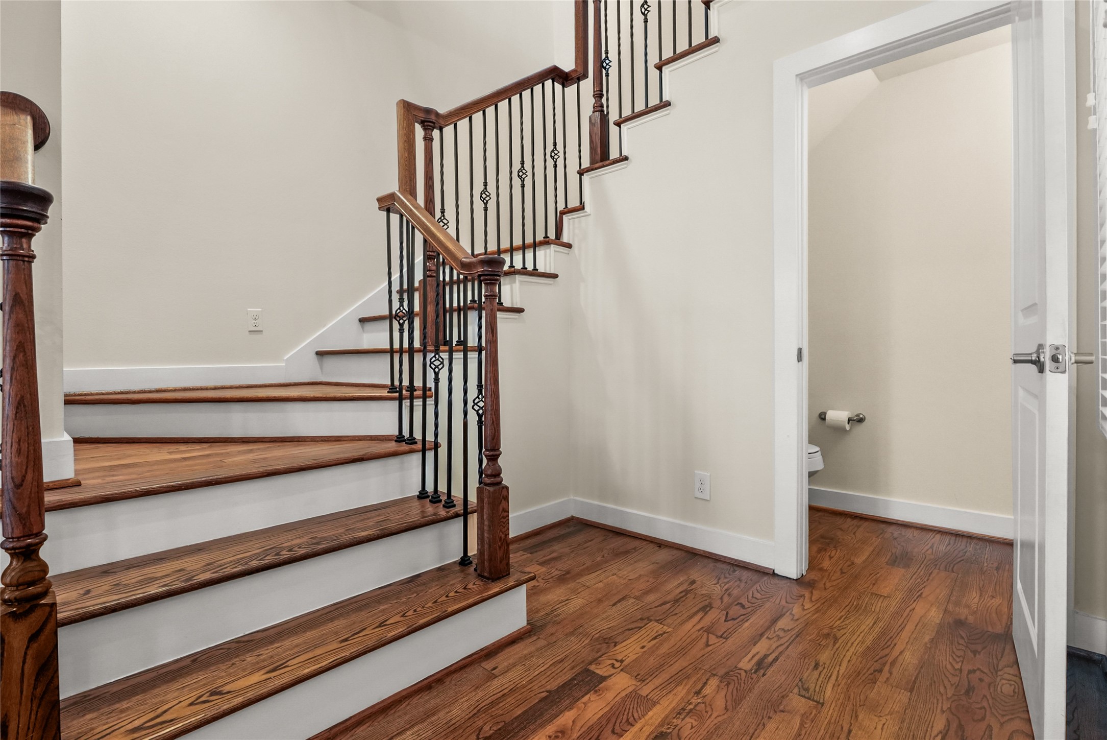4409 Schuler Street, Unit A Houston, TX 77007 - Photo 16 of 33 The entryway features hardwood flooring and a staircase with wood treads and wrought iron balusters, with a conveniently located half bathroom on the side—perfect for guest use.