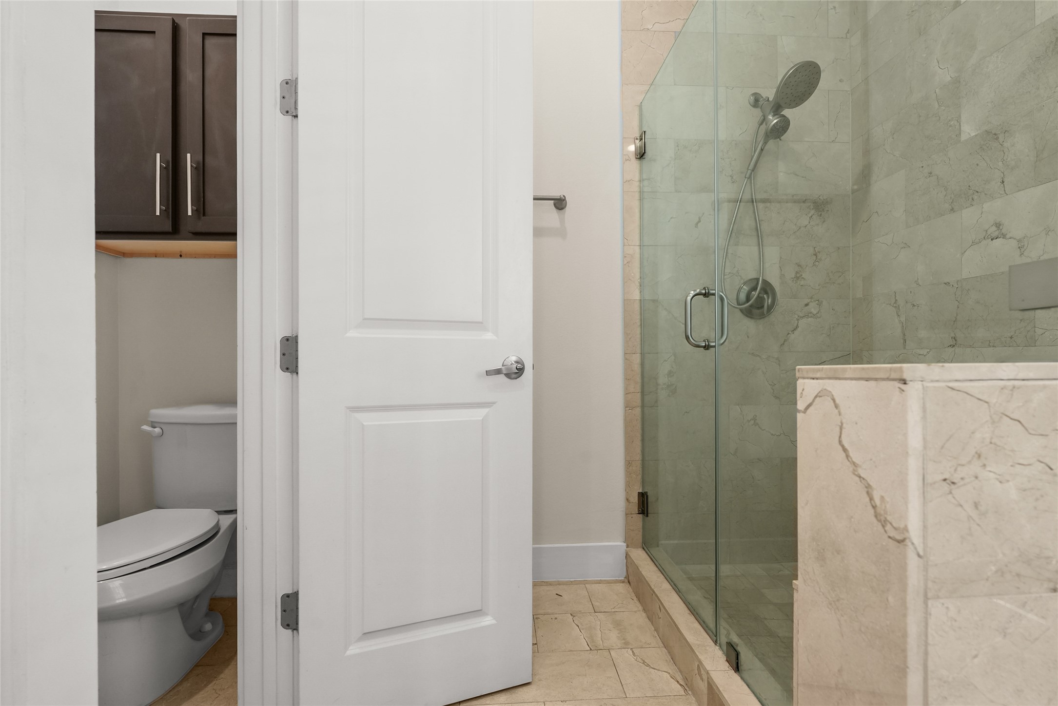 4409 Schuler Street, Unit A Houston, TX 77007 - Photo 25 of 33 Closer view of the primary bathroom reveals a glass-enclosed walk-in shower, with the toilet privately situated across behind its own door.